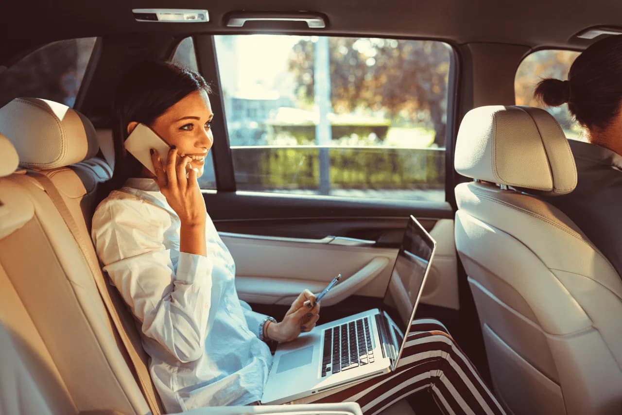 A passenger working comfortably in the back of a chauffeured car